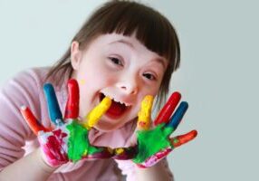 Cute little girl with painted hands. Isolated on grey background.